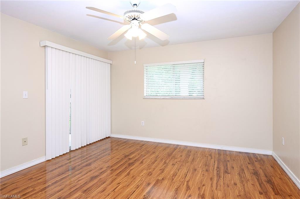 2370 Naples Trace Circle, Unit 7 Naples, FL 34109 - Photo 13 of 23 an empty room with wooden floor fan and windows