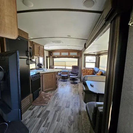 a kitchen with stainless steel appliances granite countertop a refrigerator a sink dishwasher a stove and white countertops with wooden floor