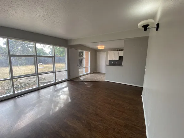 an empty room with wooden floor and windows