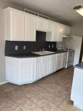 a kitchen with granite countertop a sink a stove and cabinets