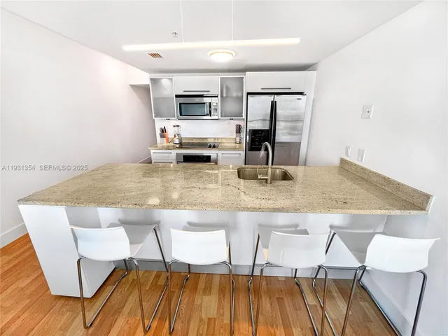 a kitchen with kitchen island granite countertop a sink and microwave