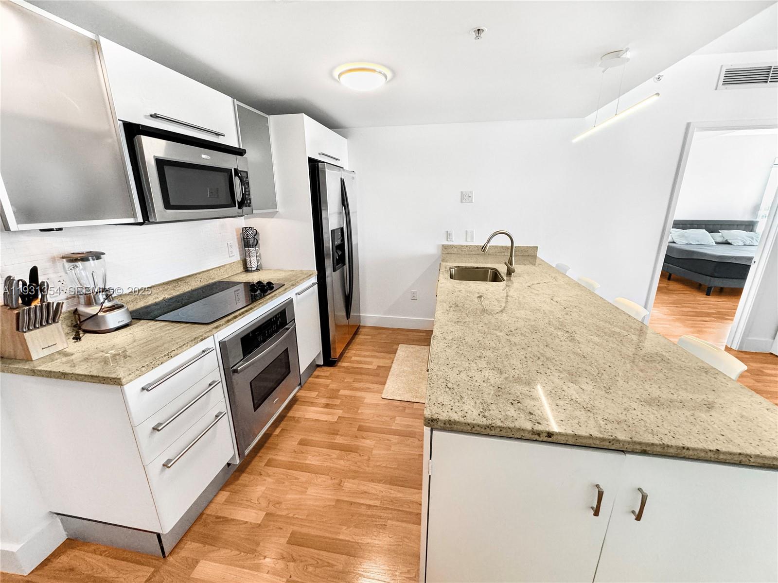 185 Southwest 7th Street, Unit 2701 Miami, FL 33130 - Photo 4 of 24 a large kitchen with granite countertop a sink and stainless steel appliances