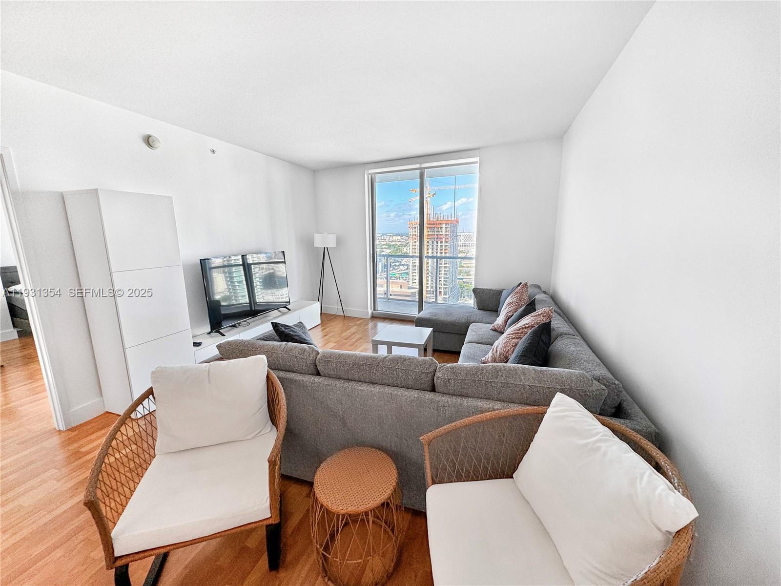 185 Southwest 7th Street, Unit 2701 Miami, FL 33130 - Photo 5 of 24 a living room with furniture a flat screen tv and a window