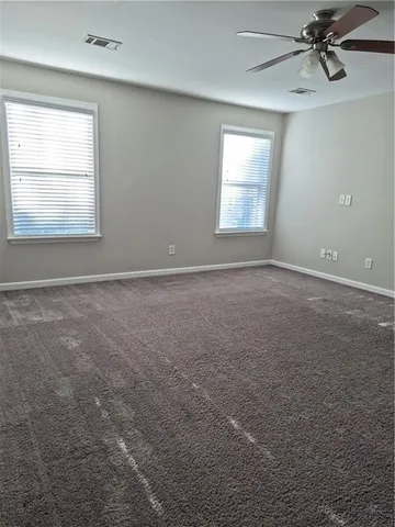 an empty room with windows and fan