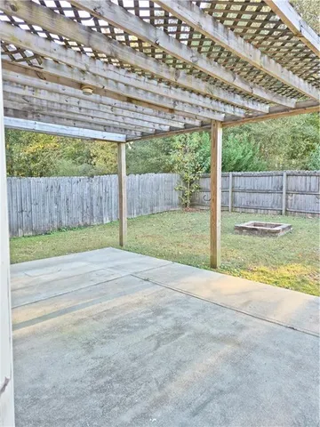 a view of a backyard with large trees and wooden fence