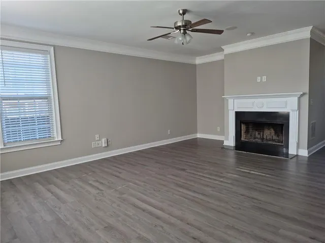 a view of an empty room with wooden floor fireplace and a window