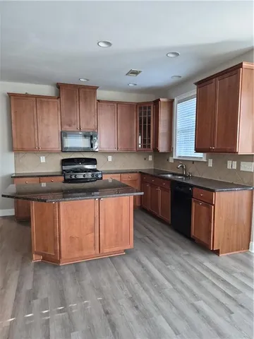 a kitchen with stainless steel appliances granite countertop a stove a sink dishwasher and a microwave oven with wooden floor