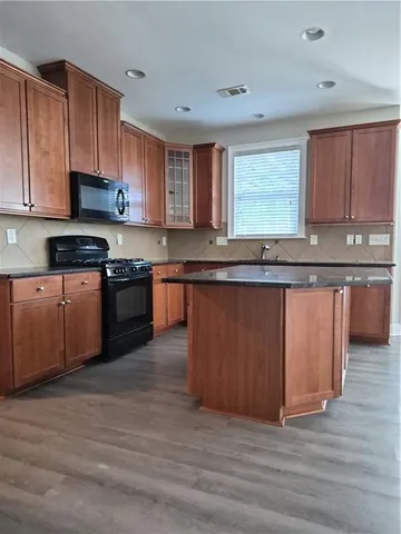 a large kitchen with granite countertop a stove top oven a sink and dishwasher with cabinets