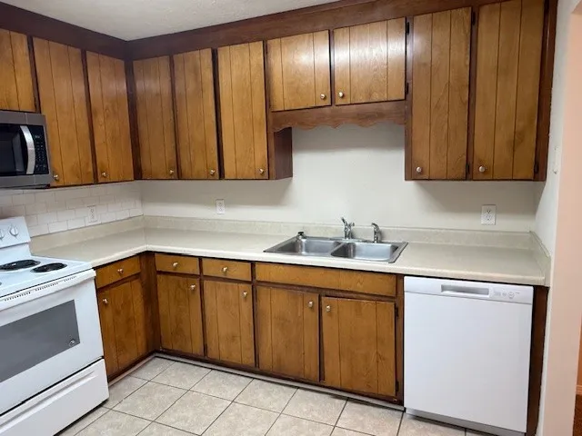a kitchen with granite countertop stainless steel appliances wooden cabinets a sink and a counter top