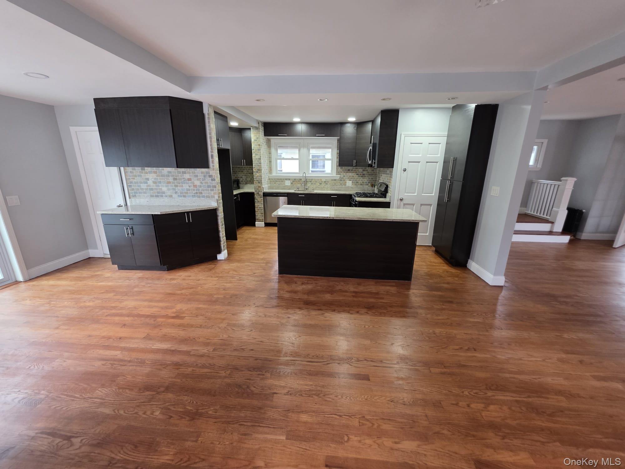 109-73 200th Street Queens, NY 11412 - Photo 7 of 12 a large kitchen with kitchen island granite countertop a stove top oven a sink and a refrigerator