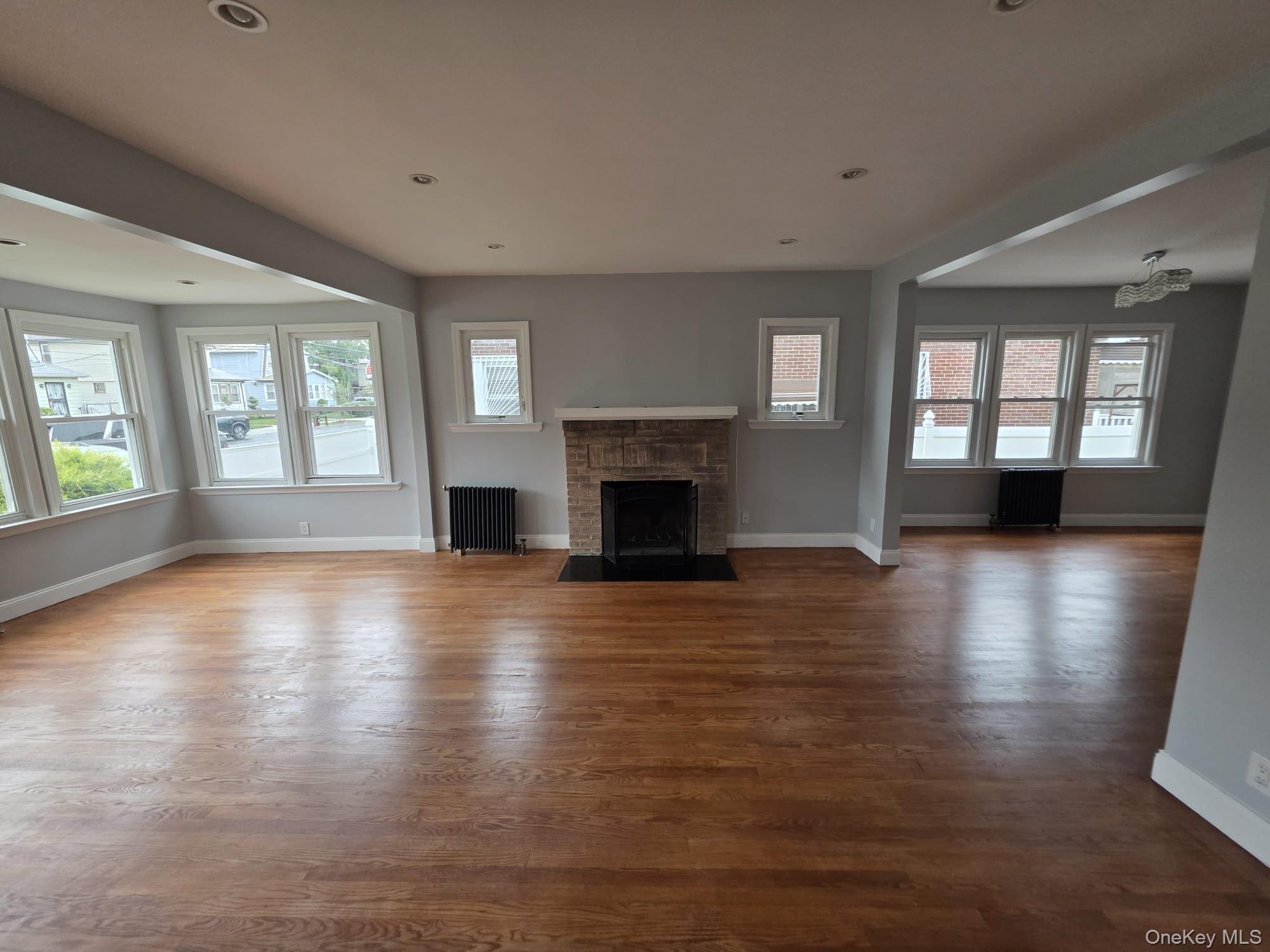 109-73 200th Street Queens, NY 11412 - Photo 9 of 12 an empty room with wooden floor and a fireplace