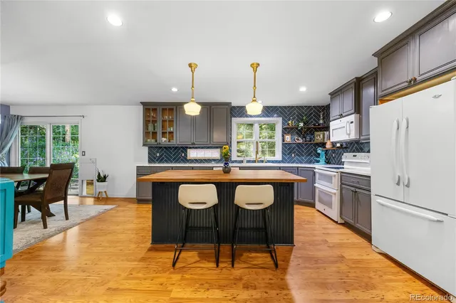 a kitchen with stainless steel appliances granite countertop a sink a stove a refrigerator cabinets and chairs
