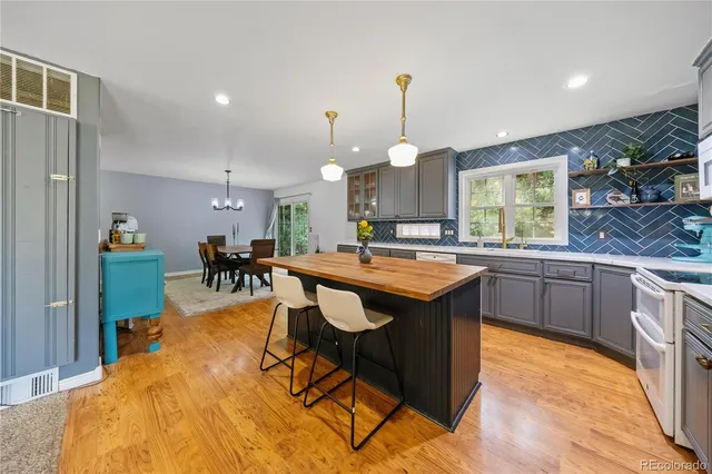 a kitchen with stainless steel appliances granite countertop a sink a stove and a wooden floors