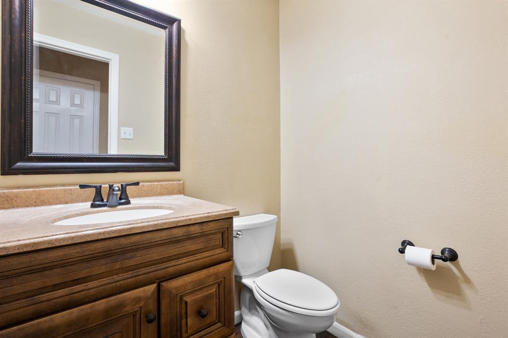 7517 Point Reyes Drive Fort Worth, TX 76137 - Photo 21 of 30 Vanity featuring a built-in sink, dark wood-finish cabinetry, and a light-toned countertop