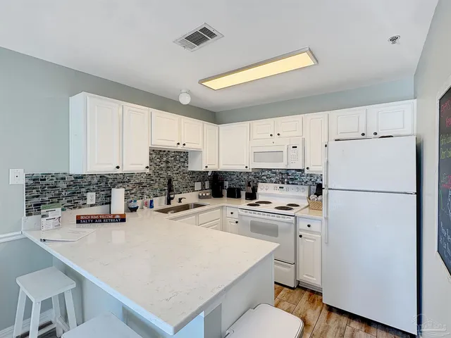 a kitchen with white cabinets and white appliances