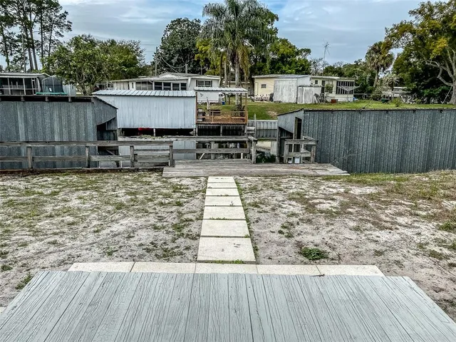 a view of a roof deck with table and chairs a barbeque with wooden floor and fence