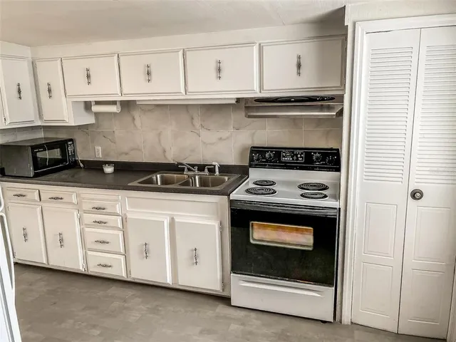 a kitchen with white cabinets and appliances