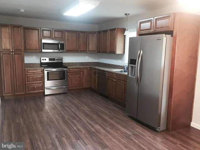a kitchen with granite countertop a refrigerator stove and microwave