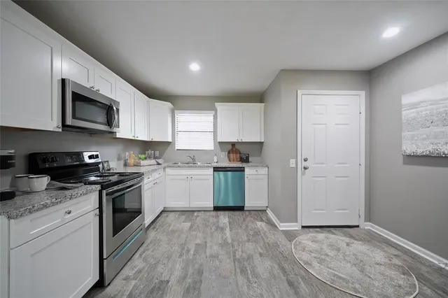 a kitchen with granite countertop white cabinets and stainless steel appliances