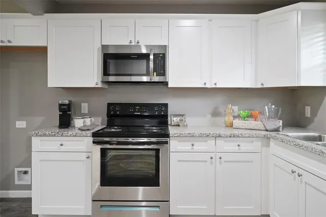 a kitchen with granite countertop white cabinets and stainless steel appliances