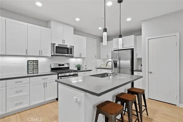 a kitchen with a refrigerator a stove a sink and chairs