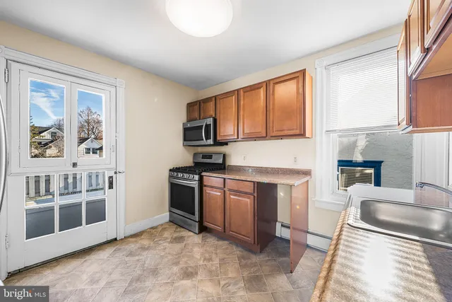 a kitchen with stainless steel appliances granite countertop a stove top oven a sink a dining table and chair with wooden floor