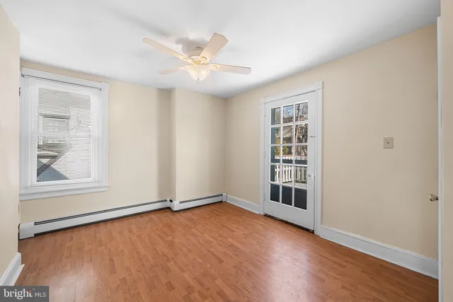 an empty room with wooden floor cabinet and windows