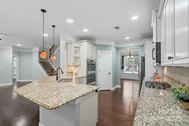 a large kitchen with stainless steel appliances granite countertop a stove a sink and a microwave