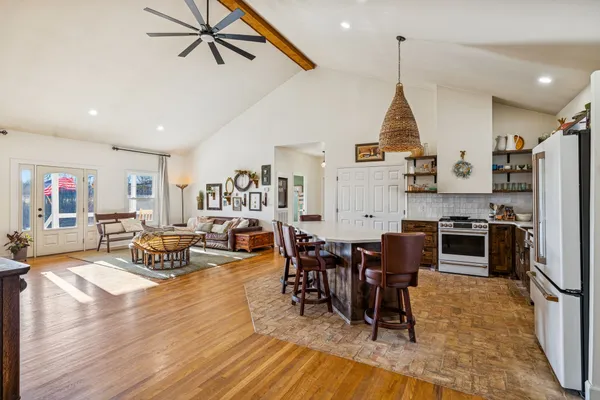 a living room with stainless steel appliances kitchen island granite countertop furniture and a wooden floor