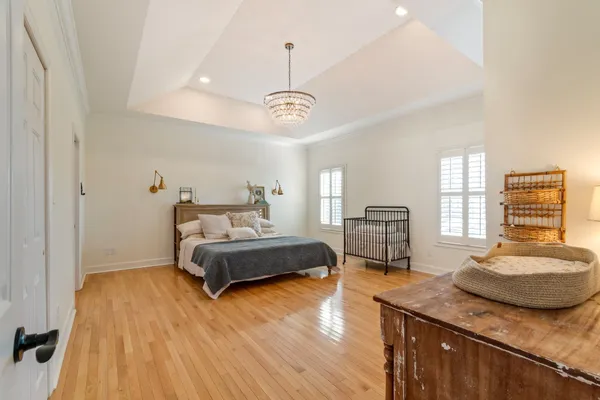 a spacious bedroom with a bed and wooden floor
