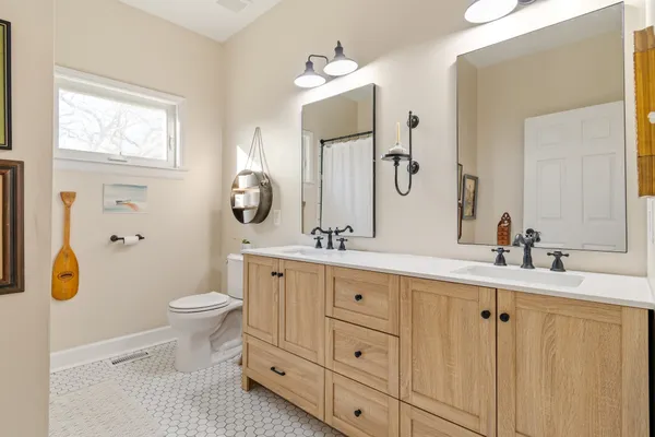 a bathroom with double vanity sink a mirror a toilet and a window