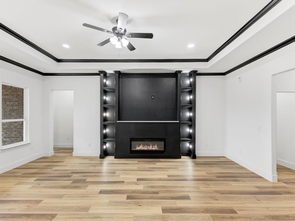 544 Shepherd Road Combine, TX 75159 - Photo 7 of 36 Unfurnished living room featuring light wood-style floors, ceiling fan, a fireplace, a tray ceiling, and ornamental molding