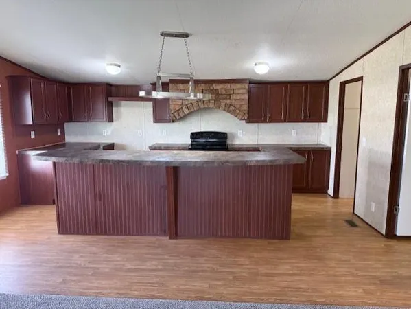 a kitchen with kitchen island granite countertop wooden cabinets and a sink
