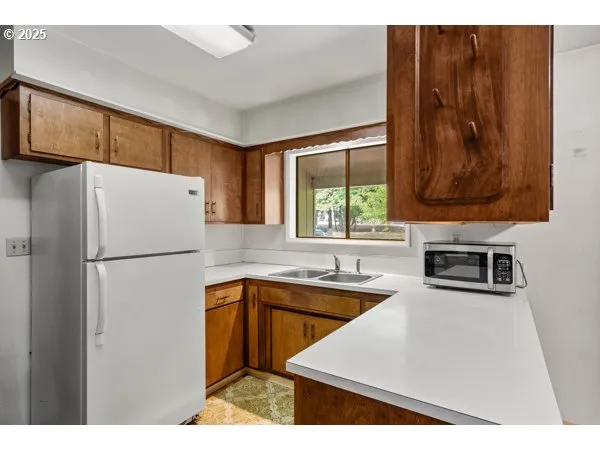 a kitchen with stainless steel appliances a refrigerator a sink a stove and white cabinets