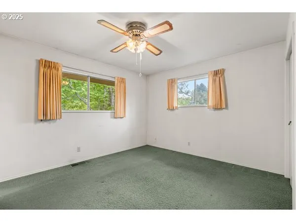 an empty room with windows and fan