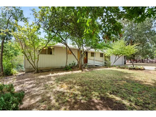 a backyard of a house with large trees and wooden fence