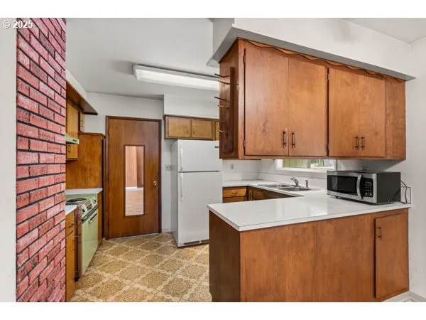 a kitchen with stainless steel appliances granite countertop a refrigerator a stove and a sink with wooden cabinets