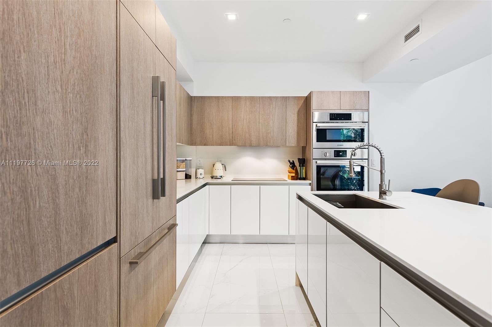 455 Northeast 39th Street, Unit 112 Miami, FL 33137 - Photo 5 of 40 a kitchen with kitchen island a counter top space a sink and cabinets