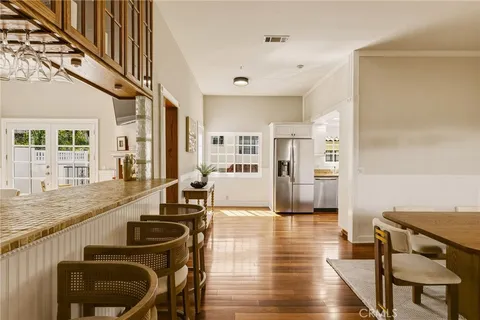 a kitchen with stainless steel appliances granite countertop white cabinets a sink a stove a microwave and wooden floors