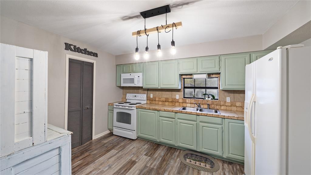 14260 North 3rd Street Scurry, TX 75158 - Photo 5 of 13 Kitchen featuring green cabinetry, white appliances, dark wood finished floors, backsplash, and hanging light fixtures