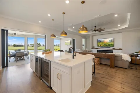 a view of a kitchen with kitchen island a large counter top a sink a stove and wooden floor