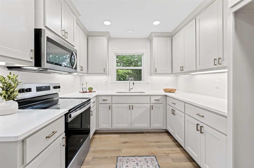 608 Bunny Rabbit Road Athens, TX 75751 - Photo 13 of 33 Bright kitchen featuring white shaker cabinetry, stainless steel appliances, white countertops, a window over the sink, and wood-finish flooring