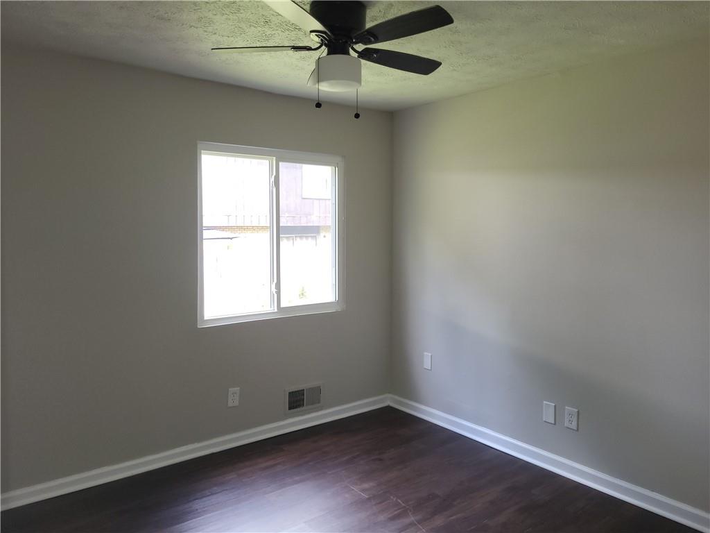 1867 Myrtle Drive Southwest, Unit 26 Atlanta, GA 30311 - Photo 11 of 15 an empty room with wooden floor fan and windows