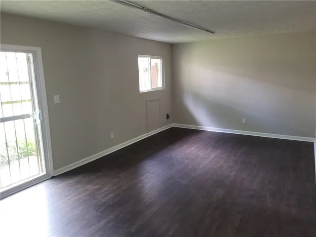 an empty room with wooden floor and windows