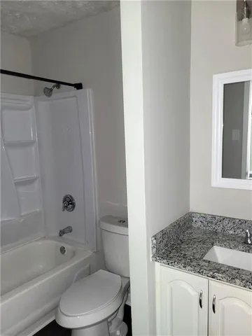 a bathroom with a granite countertop sink toilet and shower