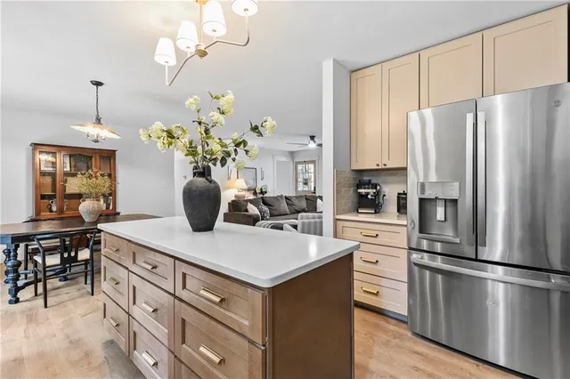 a kitchen with a refrigerator a white cabinets a stove and a chandelier