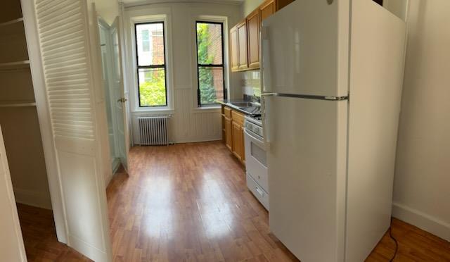 72-53 65th Place Queens, NY 11385 - Photo 2 of 7 Kitchen featuring white appliances, radiator, and light wood finished floors