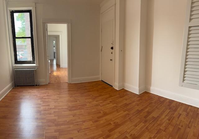72-53 65th Place Queens, NY 11385 - Photo 3 of 7 Unfurnished room with radiator and light wood-style floors