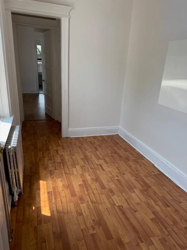 72-53 65th Place Queens, NY 11385 - Photo 4 of 7 Corridor featuring radiator heating unit and light wood-style floors