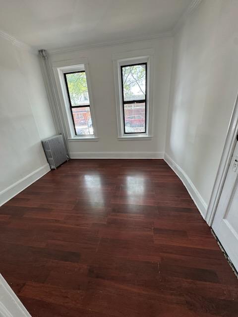 72-53 65th Place Queens, NY 11385 - Photo 6 of 7 Empty room with radiator, crown molding, and wood finished floors
